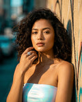 Woman wearing a strapless iridescent top against a graffiti-covered wall.
