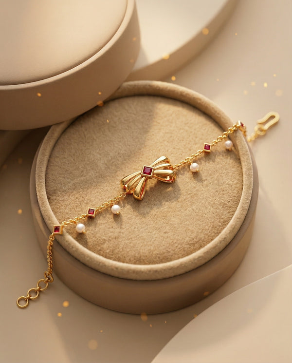 Gold bracelet with red gemstones and pearls on a beige jewelry box