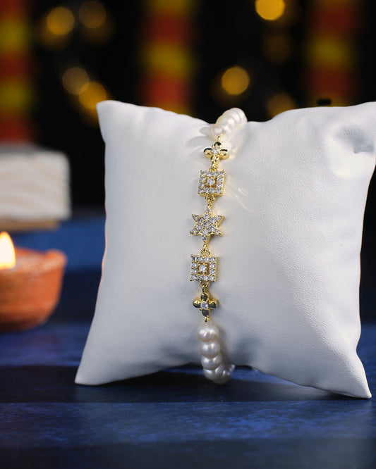 The Dagny Pear Bracelet by Chandrani Pearls, featuring star and square diamonds, is elegantly displayed on a white cushion beside an unlit candle on a blue surface.