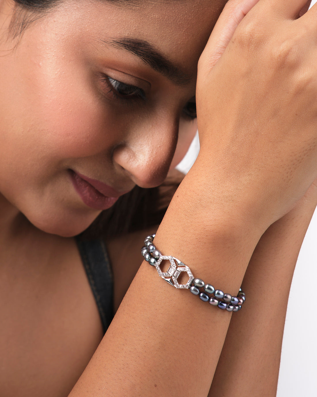 The Trendy Black 2 Line Pearl Bracelet by Chandrani Pearls India features elegant double strands of black pearls and a geometric silver clasp with diamonds, perfectly showcased on a light yellow surface for everyday luxury.