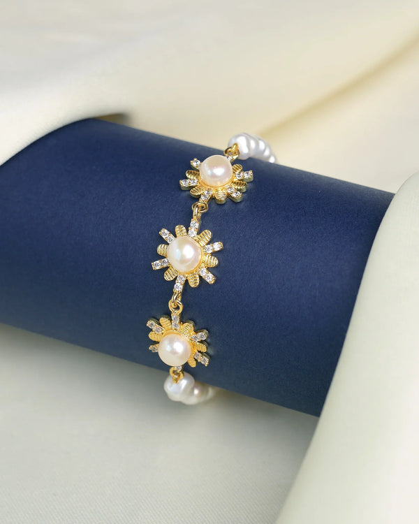 The Graceful Pearl & CZ Link Bracelet by Chandrani Pearls features daisy-shaped flower links with pearl centers and cubic zirconia, displayed on a navy blue holder against a cream fabric background.