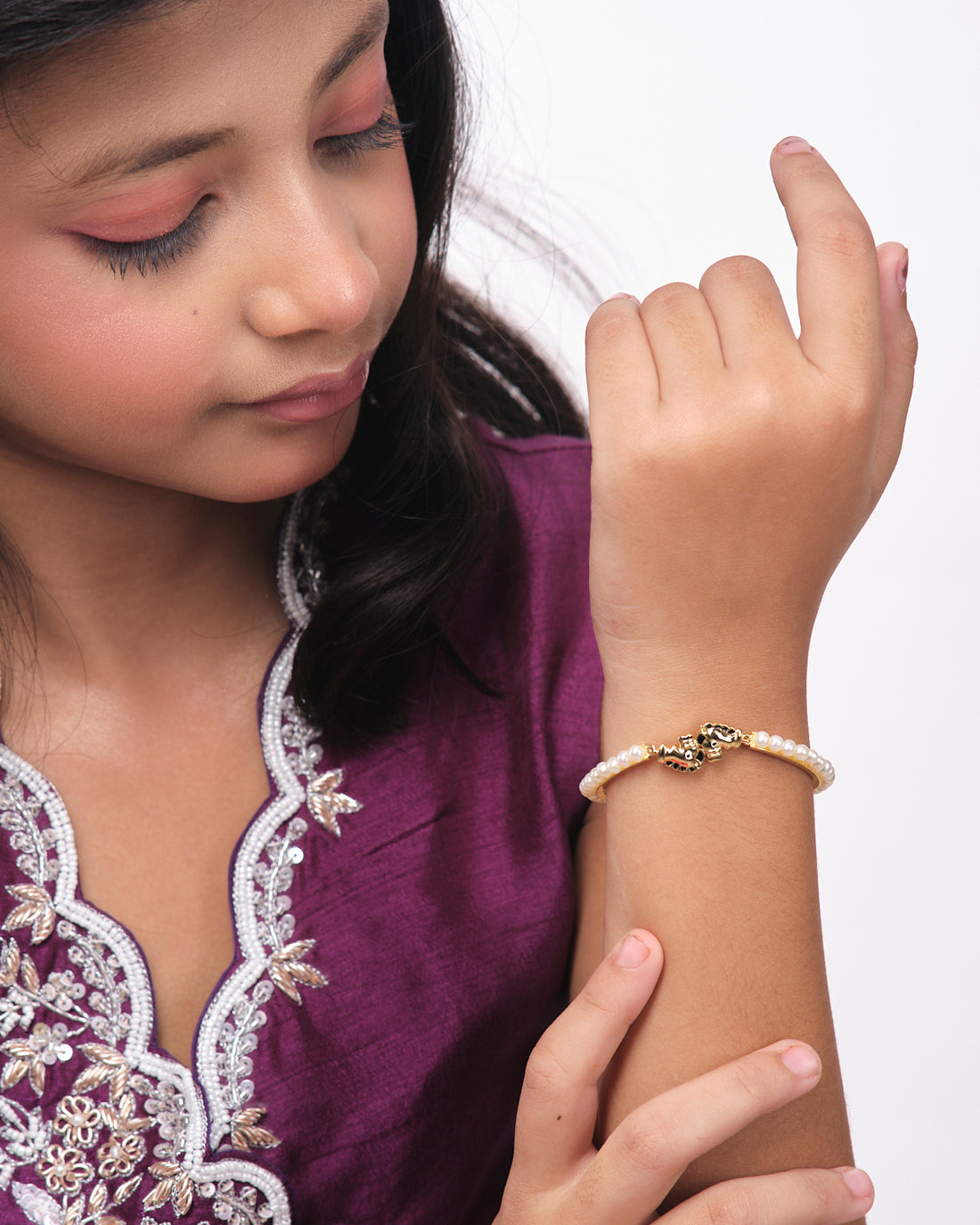 Horse Pearl Bangle for kids by Chandrani Pearls India showcased on a cylindrical stand with a white and dark blue backdrop.