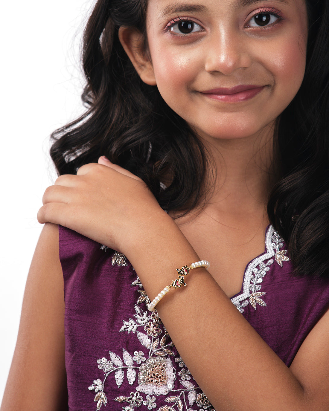 The Monkey Pearl Bangle for kids by Chandrani Pearls India, showcased with gold cartoon character charms, is set against a white and dark background with cloud-like cutouts.