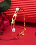 The Quad and Pearl 925 Silver Bangles by Chandrani Pearls India feature a geometric centerpiece, pearls, and a chain clasp, elegantly displayed on a red surface beside a red rose.