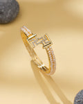 Swasthik White Pearl & CZ Cuff Bangle by Chandrani Pearls—a chic statement piece with two rows of small pearls, CZ stones, and a geometric clasp, styled on a light beige surface with smooth gray stones in the background.