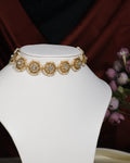The Ravishing CZ Studded Choker by Chandrani Pearls India features elegant circular, floral-inspired designs with white stones and pearls, displayed on a white stand for a radiant look.