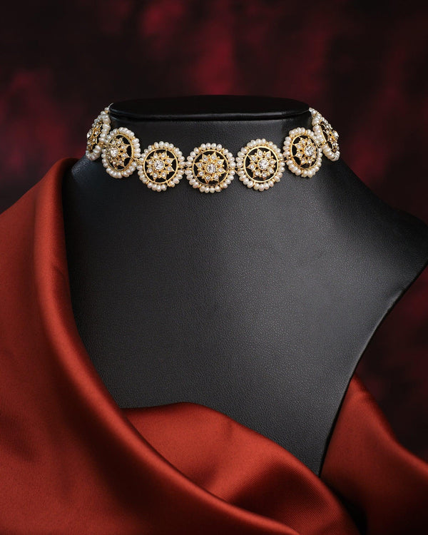 The Kanakshobha-Golden Grace Traditional Pearl Choker by Chandrani Pearls is shown on a black mannequin with draped dark red fabric and background—a timeless, elegant accessory for classic style.
