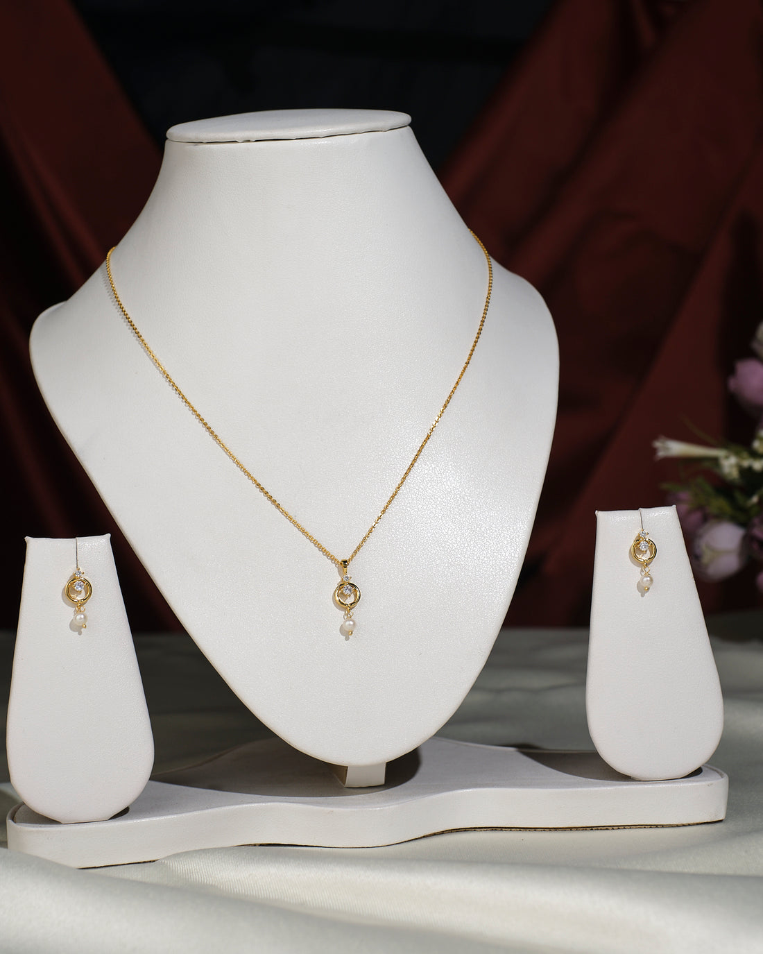 The Simple Pendant Set by Chandrani Pearls India, featuring a circular necklace and matching earrings, is elegantly displayed on a white jewelry stand, showcasing modern style against a dark background.