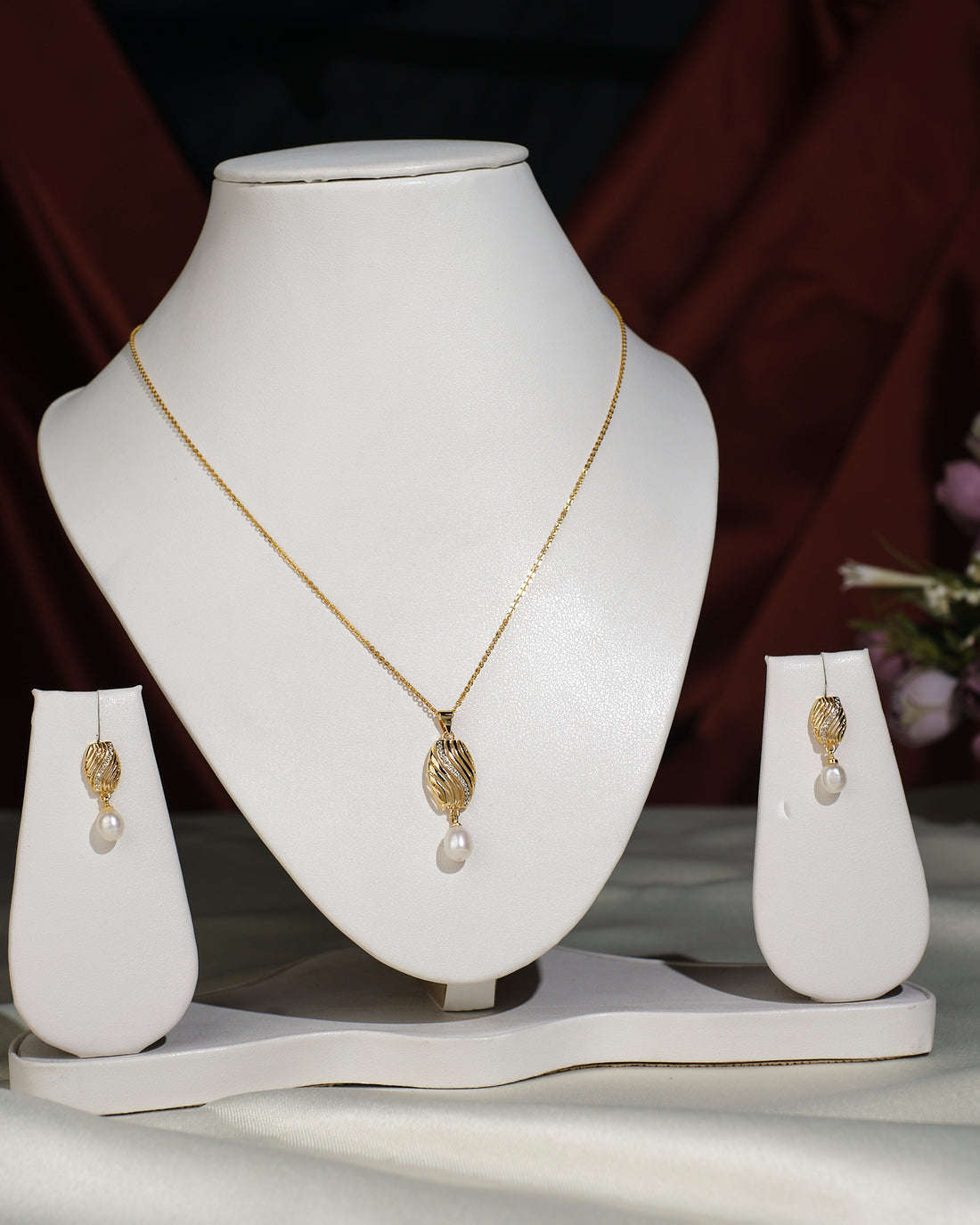 The Pretty Pendant Set by Chandrani Pearls India features elegant leaf-shaped pendants with pearl drops, styled on a white jewelry stand—an exquisite choice to enhance any ensemble. (Chain used for photographic purpose.).