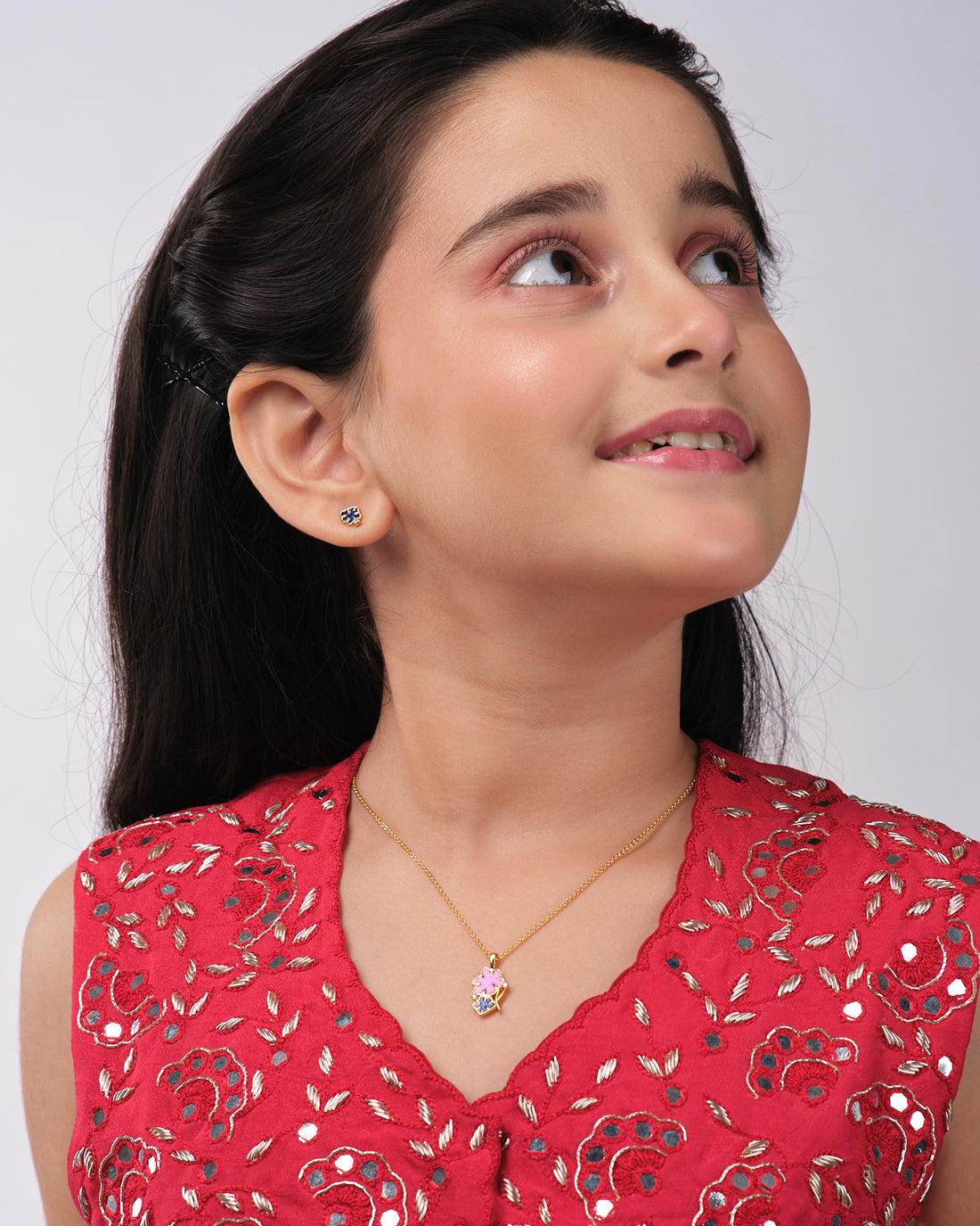 The Floral Enamel Pendant Sets by Chandrani Pearls India include a gold necklace with a pink flower and black clover pendant, paired with black clover stud earrings, displayed against a wizard silhouette and star background.