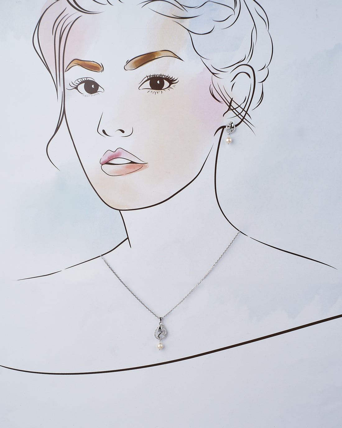 The Marina 925 Silver Pendant Set by Chandrani Pearls India features pearl drops and crystal accents, exuding sophistication. Displayed on a light pink card, it is beautifully surrounded by red roses.