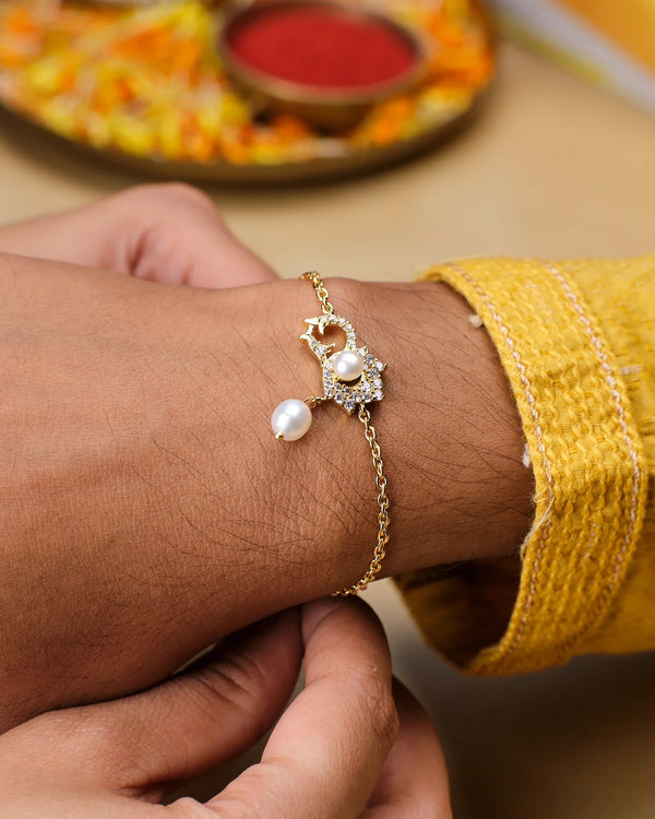 A person wearing the Go With The Flow Pearl Bracelet by Chandrani Pearls, paired with a yellow outfit, adjusts the accessory on their wrist. A decorated plate in the background enhances the timeless elegance of this look.