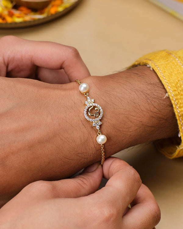 A close-up shows a wrist adorned with the Chandrani Pearls Exquisite OM Pearl Bracelet, featuring gold freshwater pearls and a circular, stone-studded OM centerpiece; another hand adjusts the elegant spiritual jewelry.