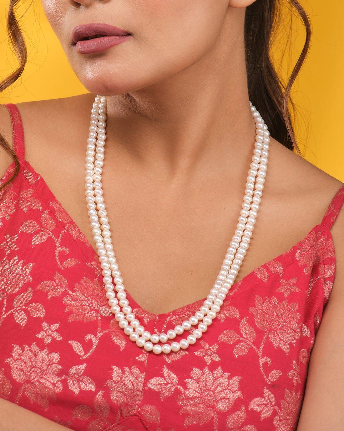 The Classic Single-Strand Pearl Necklace by Chandrani Pearls is displayed on a navy blue velvet bust, with cream-colored fabric draped in the background.
