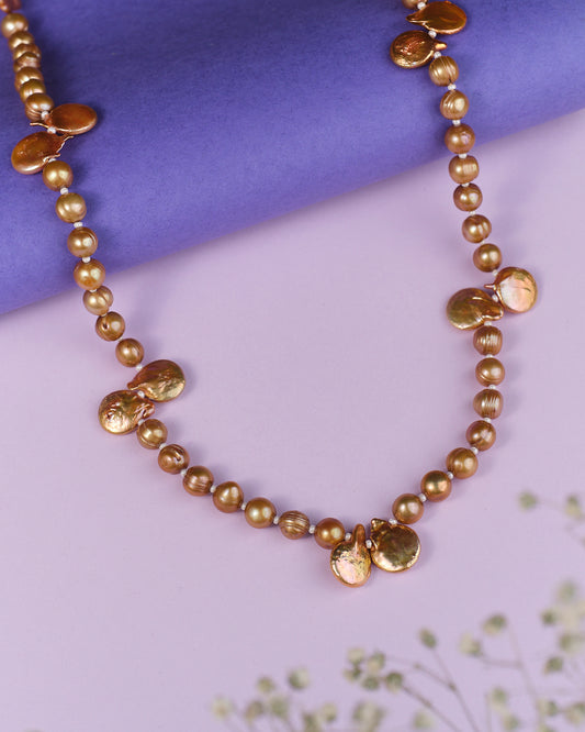 The Umpteen Blossom Pearl Necklace by Chandrani Pearls exudes refined elegance with its irregularly shaped gold accents set against a purple background.