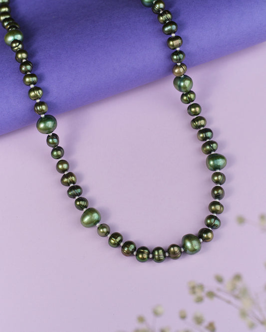 The Forest Essential Pearl Necklace by Chandrani Pearls exudes elegance and charm with its green pearls displayed against a vibrant purple background.