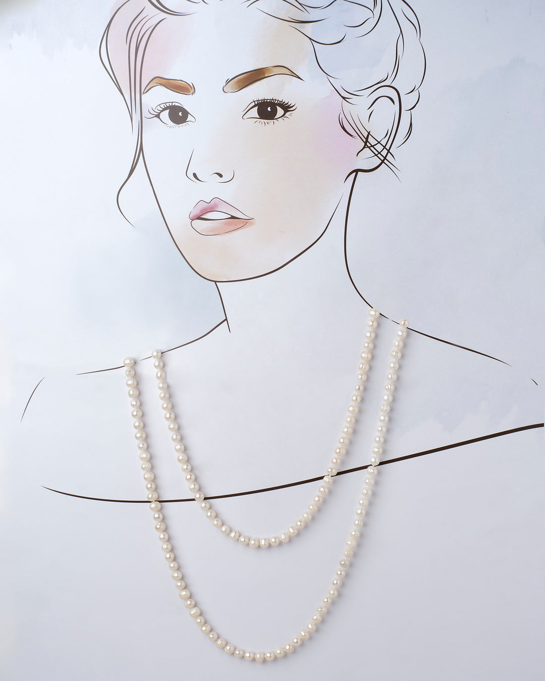 The Heavenly Pearl Necklace by Chandrani Pearls features elegant white pearls arranged in a circular form on a purple and pink background with delicate white flowers in the foreground.