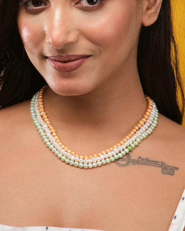 A woman wears Chandrani Pearls' Elegant Patriotism Limited Edition Pearl Necklace in white, peach, and green with a "Patience is" tattoo and an arrow on her collarbone—a standout among women's accessories.
