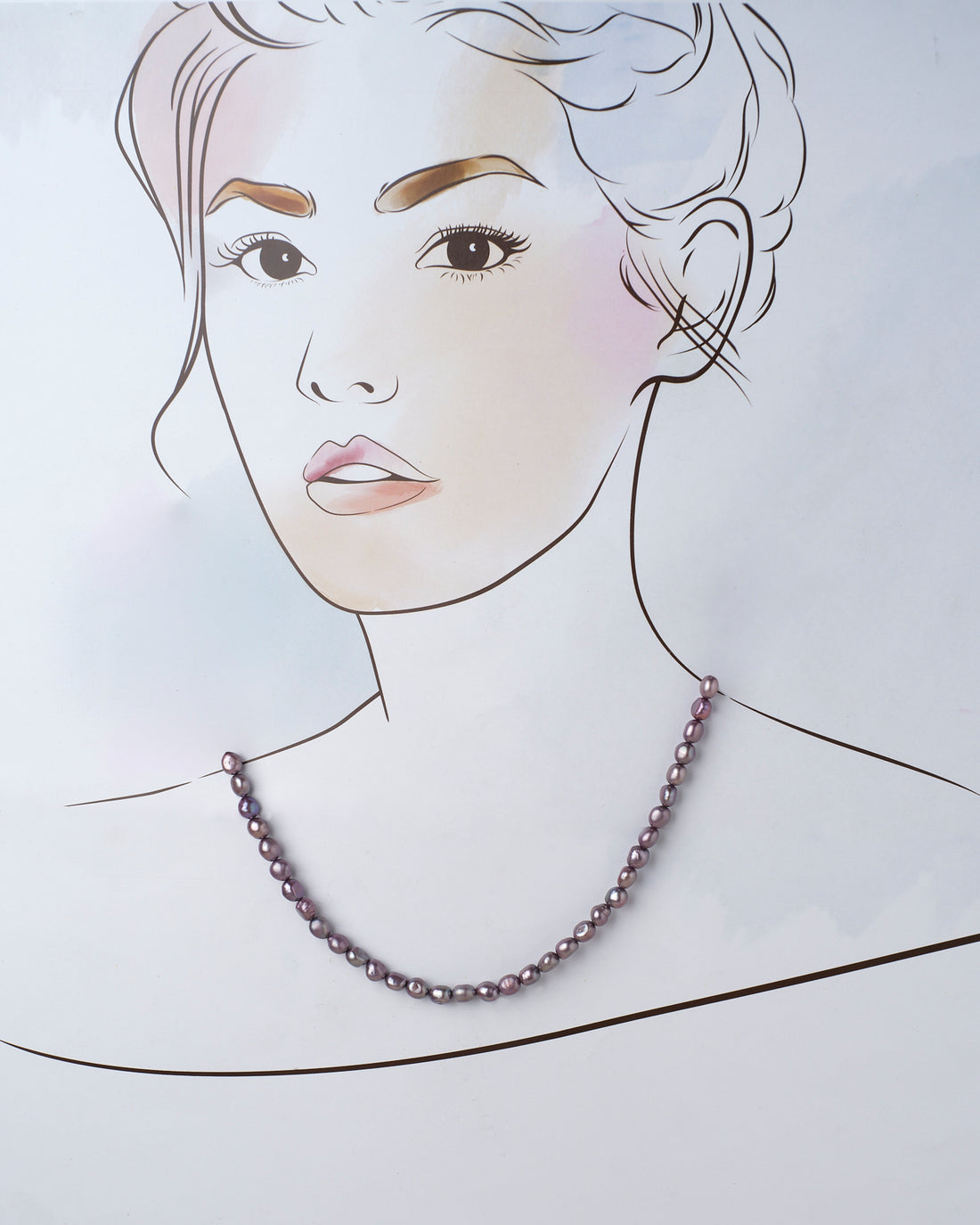 The Splashy Sleet Pearl Necklace by Chandrani Pearls, a blend of purple and pink pearls, elegantly rests on a lavender surface with a blurred floral decoration in the foreground.