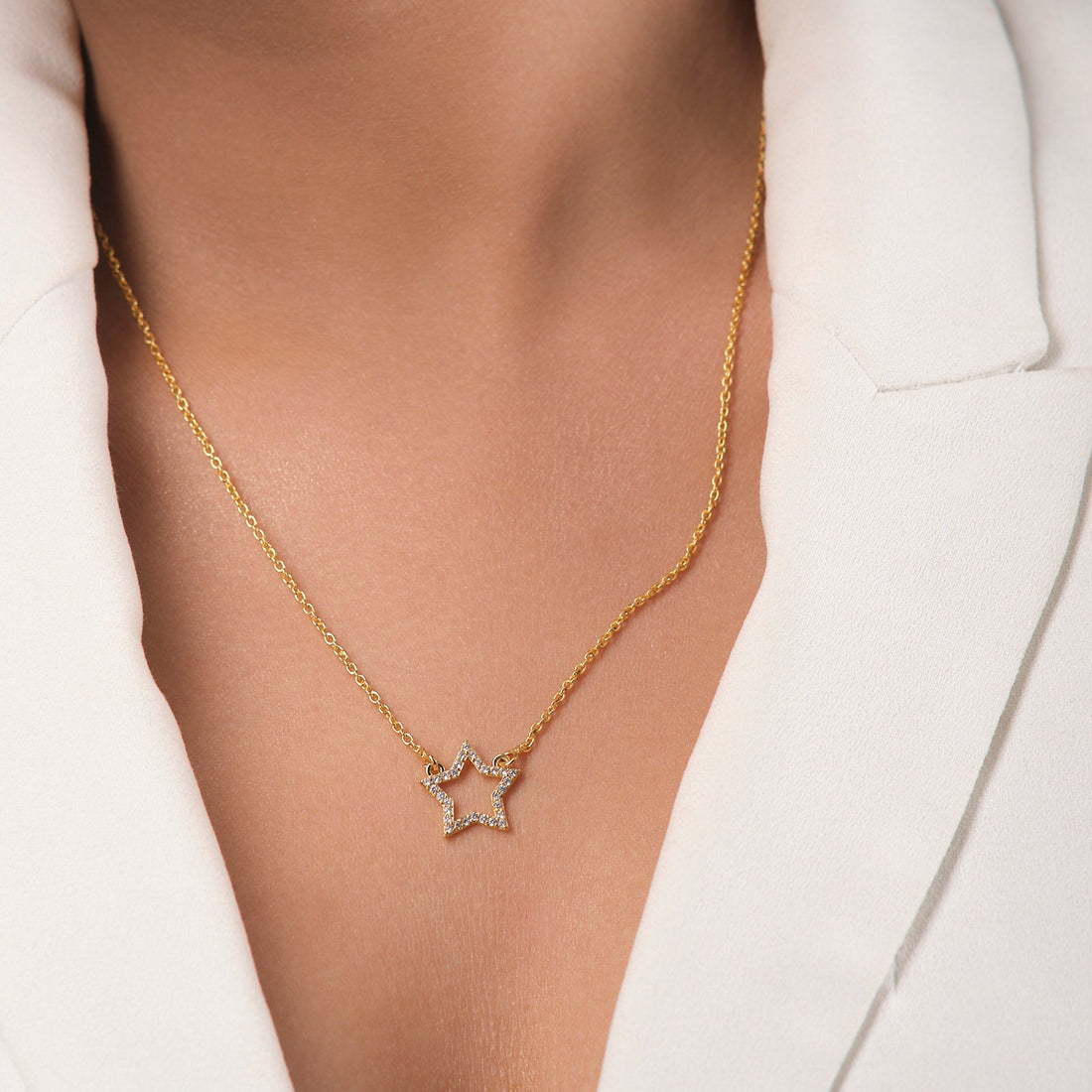 The Guiding Star Pendant by Chandrani Pearls features a star-shaped gold pendant with sparkling cubic zirconia, adding elegance to any cream-colored blazer.
