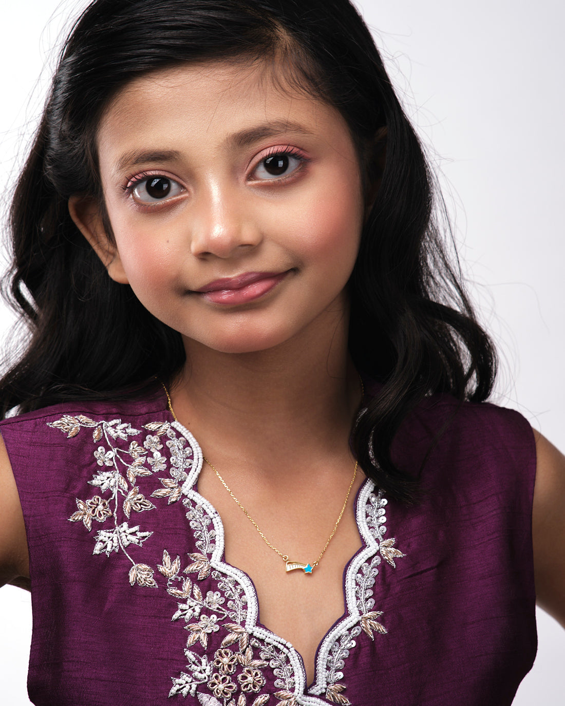 The Little Star Beautiful Pendant by Chandrani Pearls India, a gold necklace with a shooting star charm, is set against a backdrop featuring a star cutout and the silhouette of a figure holding a wand.