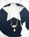 The Sleepy Cat Pretty Pendant by Chandrani Pearls India, featuring a gold finish with a fox and pearl design, is showcased against a backdrop highlighting a wizard's silhouette and star.
