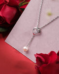 The Spindle Spin 925 Silver Pendant by Chandrani Pearls India features a pearl and heart-shaped detail, displayed on a pink card with red roses—an elegant, unique addition to any jewelry collection.