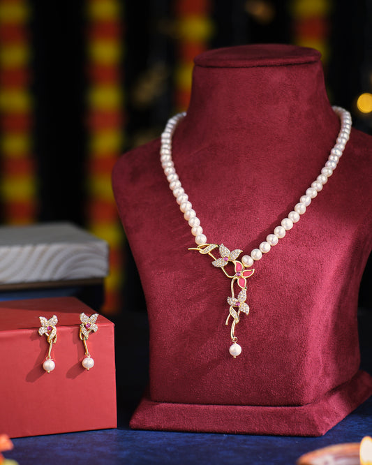 The Spring's Wish Pearl Necklace Set by Chandrani Pearls, featuring intricate floral gold detailing and matching earrings, displayed on a burgundy stand.