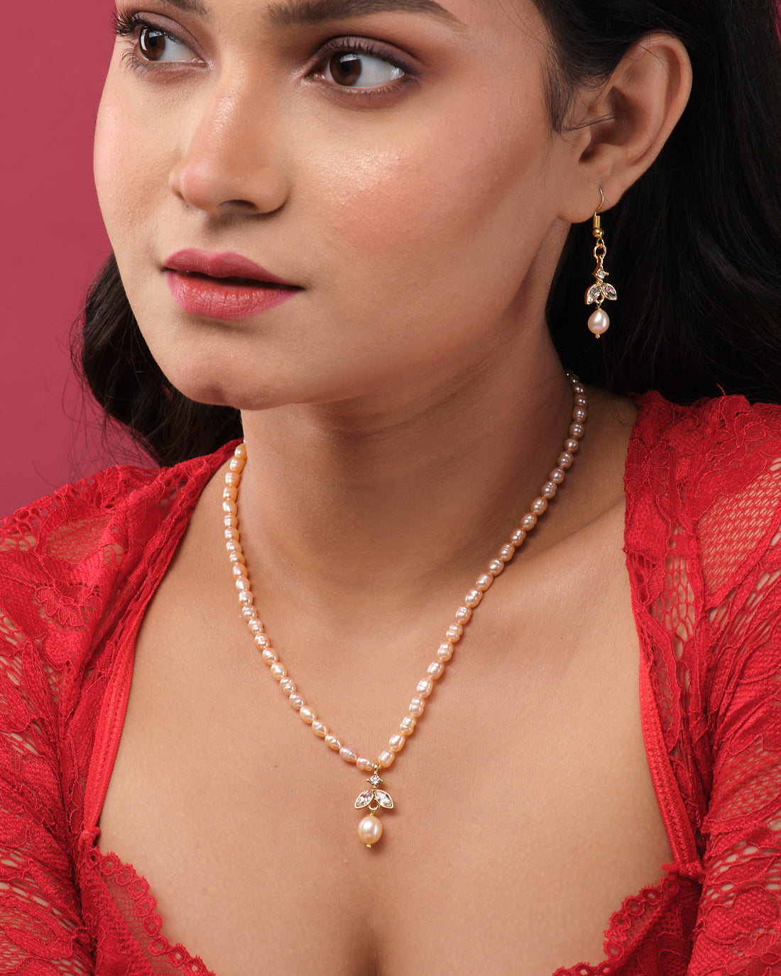 The Cute Pearl Necklace Set by Chandrani Pearls India is shown on a white stand, with a pearl necklace featuring a pendant and matching pearl drop earrings, set against draped fabric.
