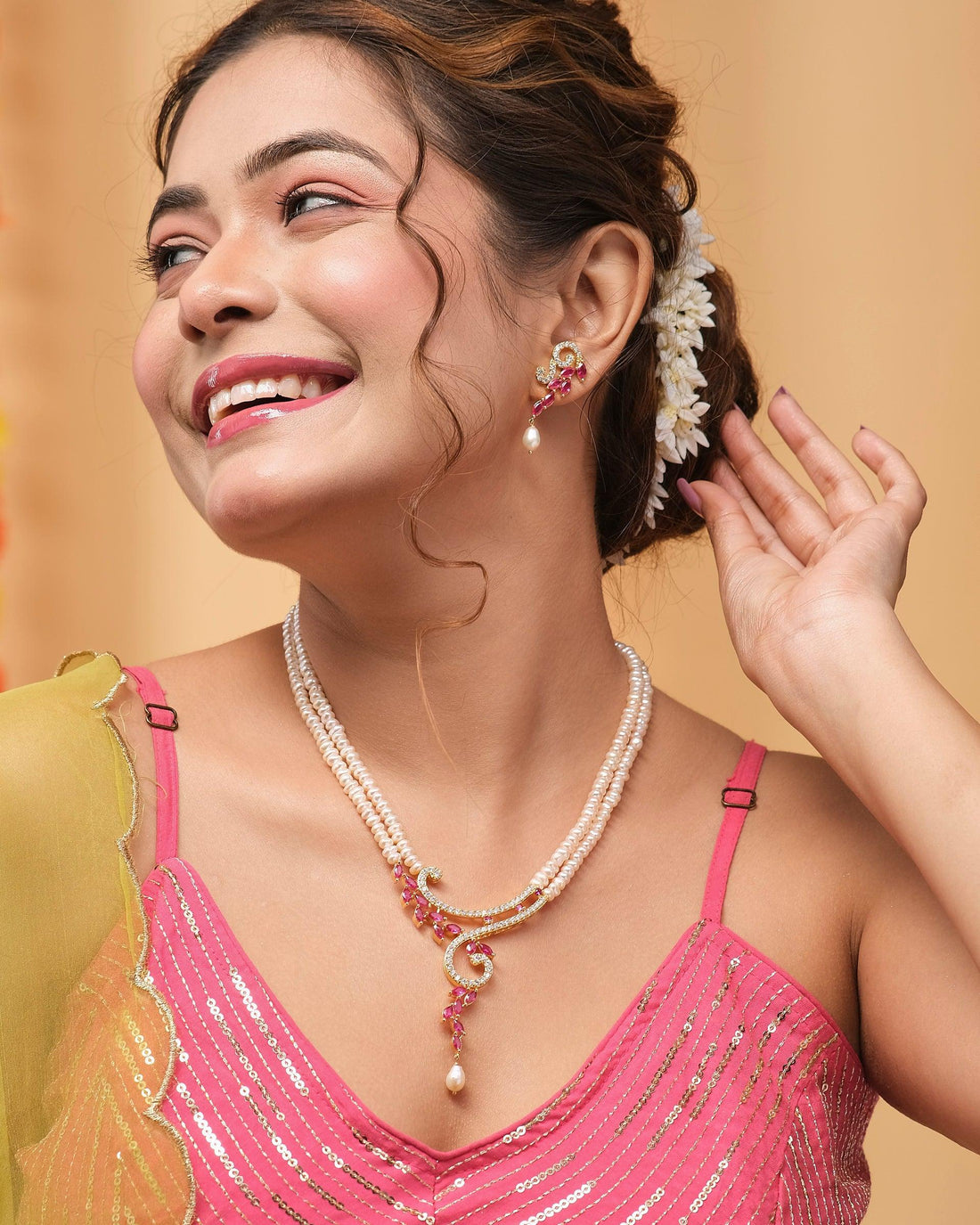 The Chaandikusuma - The Royal Bloosom Pearl Necklace Set by Chandrani Pearls features intricate gold and pink accents and is elegantly presented on a red velvet stand, alongside matching earrings in a red box.
