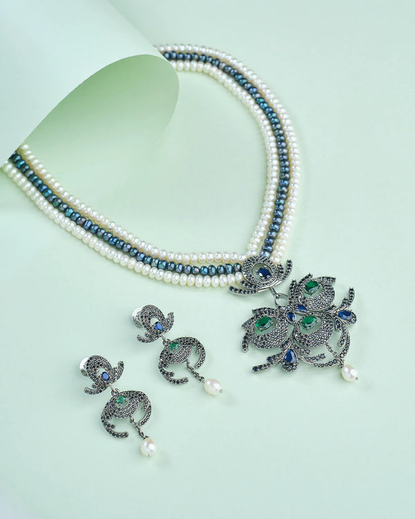 The Stylish pearl set by Chandrani Pearls, crafted to complement both ethnic and western wear, features a black-and-white beaded necklace with ornate pendant and matching earrings—perfect for elegant occasions.