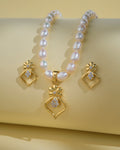 The Pretty Pearl Necklace Sets by Chandrani Pearls India, featuring a gold and diamond pendant, are displayed with matching earrings on a light yellow background.