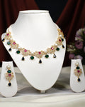 The Mosaic Marvel CZ Stone 2 Line Necklace Set by Chandrani Pearls India features chic gold tones with red, green, and pearl accents, displayed on a white stand alongside matching dangle earrings—an elegant addition to your wardrobe.