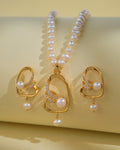 The Fashionable Pearl Necklace Sets by Chandrani Pearls India feature a gold-finish necklace and matching earrings with classic pearls and rhinestones, elegantly displayed on a light yellow background.