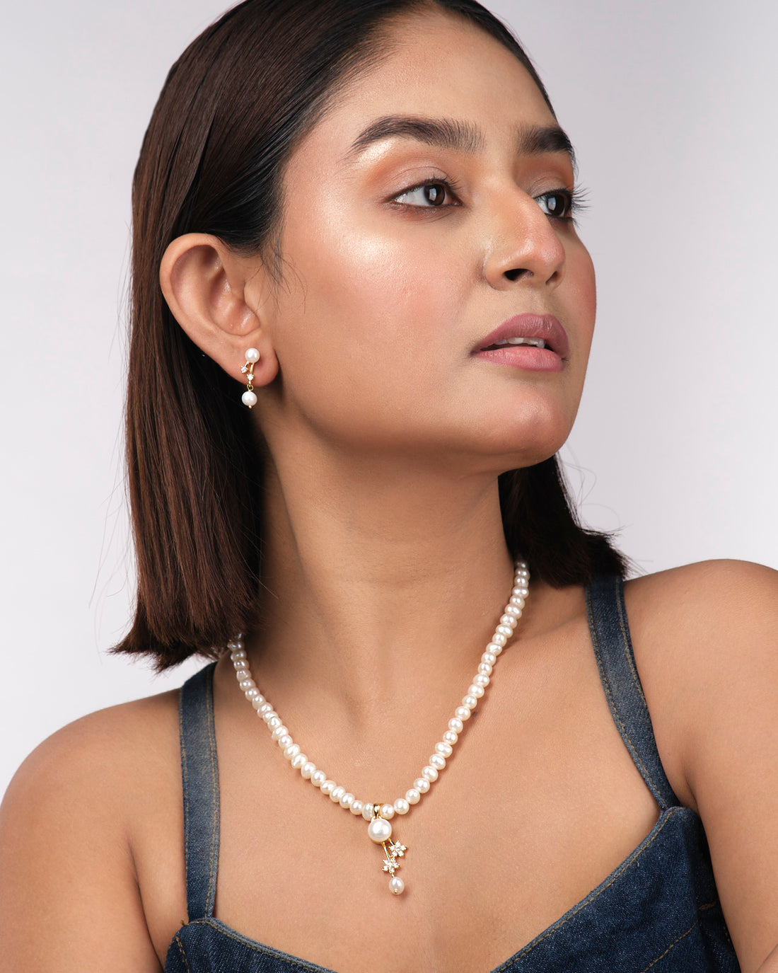 The Simple Pearl Necklace Sets by Chandrani Pearls India, featuring gold and diamond-accented pearls with matching earrings, is showcased on a soft yellow background, ideal for the modern woman.