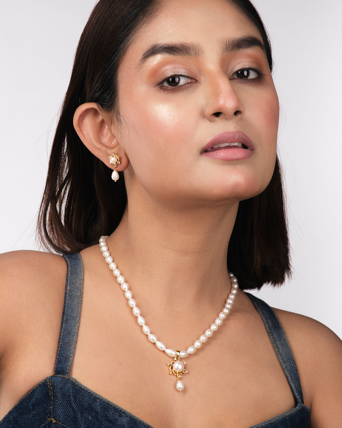 The Trendy Pearl Necklace Sets by Chandrani Pearls India feature elegant teardrop pearls and sparkling stones in a refined necklace and earrings set, perfect for the modern woman, shown on a pale yellow background.