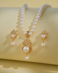 The Pretty Pearl Necklace Sets by Chandrani Pearls India, featuring a necklace and matching earrings with luminous pearls and clear stones, are displayed on a pale yellow background to accentuate their elegance.