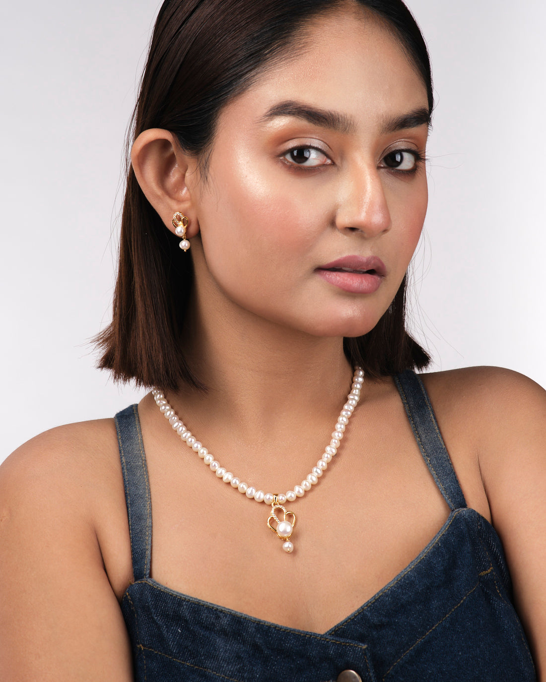 The Elegant Pearl Necklace Sets by Chandrani Pearls India, featuring a necklace and matching earrings, are displayed on a light beige background to highlight the pearls' natural beauty.