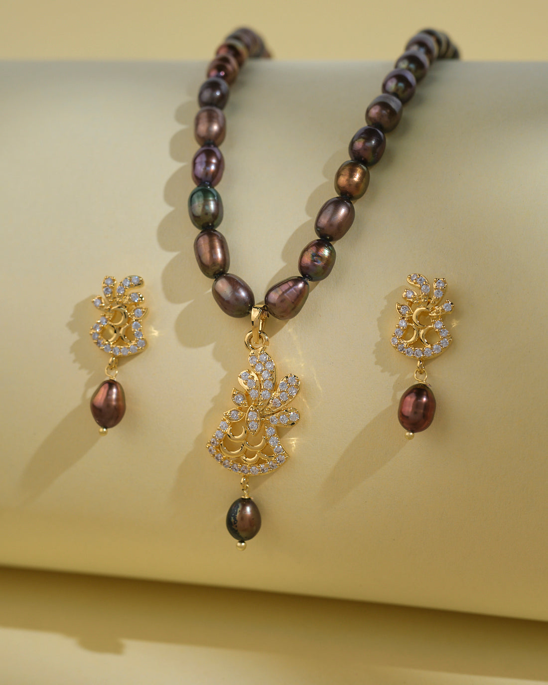 The Chandrani Pearls India Beautiful Pearl Necklace Sets feature intricate designs, pearls, and crystal accents that celebrate natural beauty against a light yellow background.