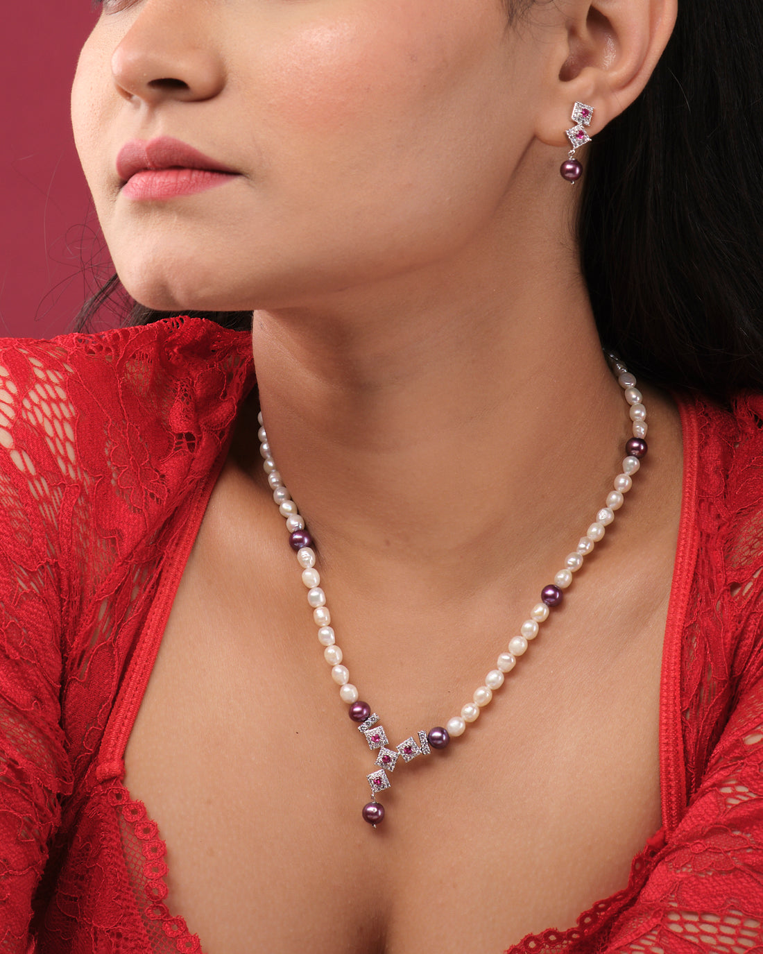 The Trendy Pearl Necklace Set by Chandrani Pearls India features pearls and amethyst beads with a matching pendant, shown on a white stand, alongside coordinating drop earrings displayed on earring stands.