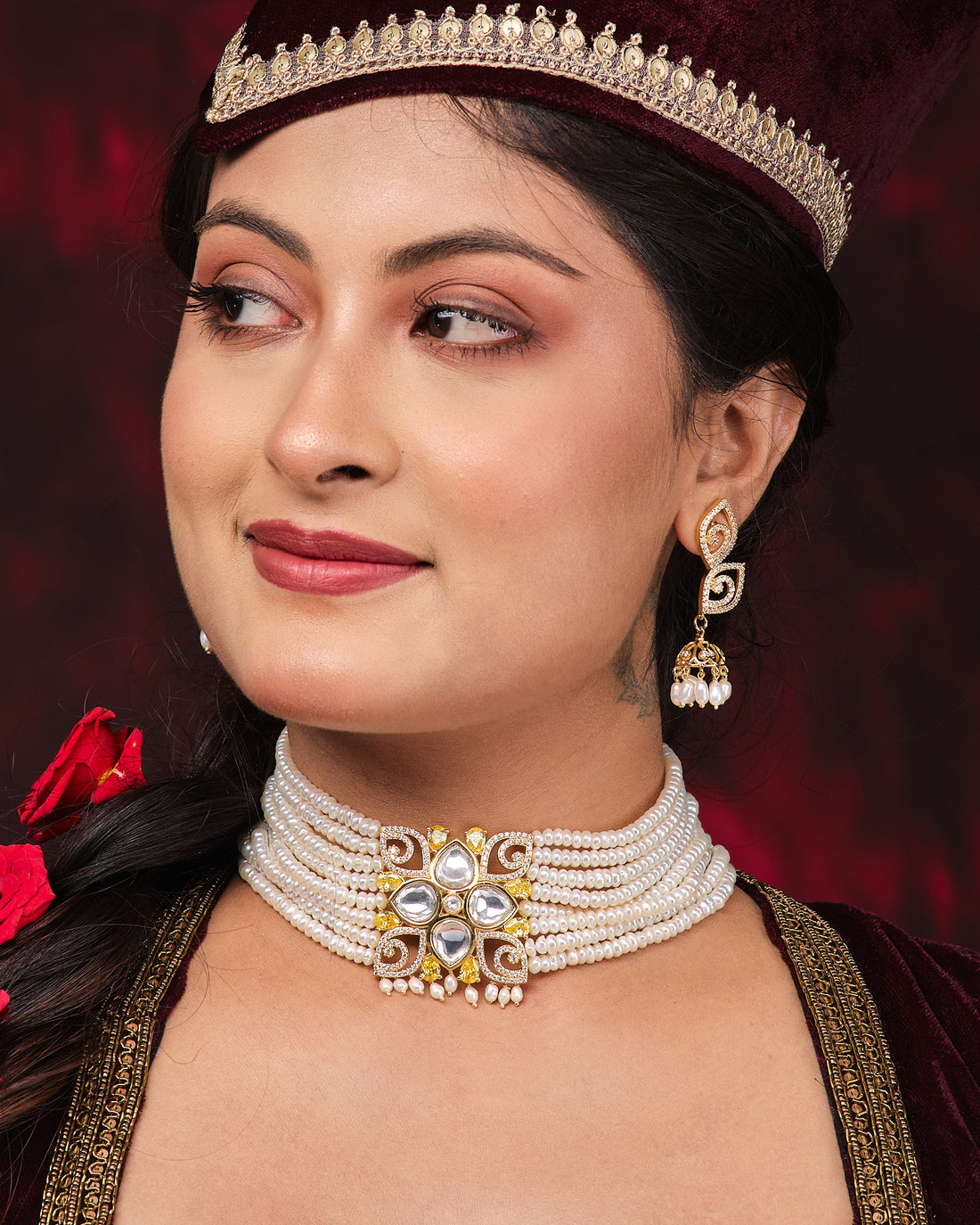 The Viveka Pearl Necklace Set by Chandrani Pearls features a vintage layered pearl necklace with a gold and gemstone floral centerpiece on a black stand, paired with matching gold and pearl earrings.