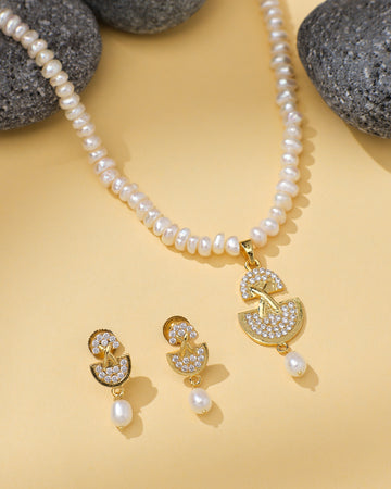 The Modern Necklace Pearl Set by Chandrani Pearls features a gold and CZ crystal pendant with matching earrings, beautifully displayed on yellow with black stones—ideal for the stylish woman.