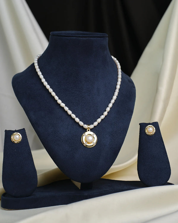 The Princess-Cut CZ Necklace Set by Chandrani Pearls is displayed on a navy blue stand, featuring a sparkling pendant and matching earrings for a bold, modern jewelry statement.