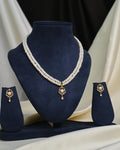 The Elegant round-cut CZ pendant with matching earrings by Chandrani Pearls, displayed on a navy stand, offers timeless style—designed to add everyday sparkle to your look.