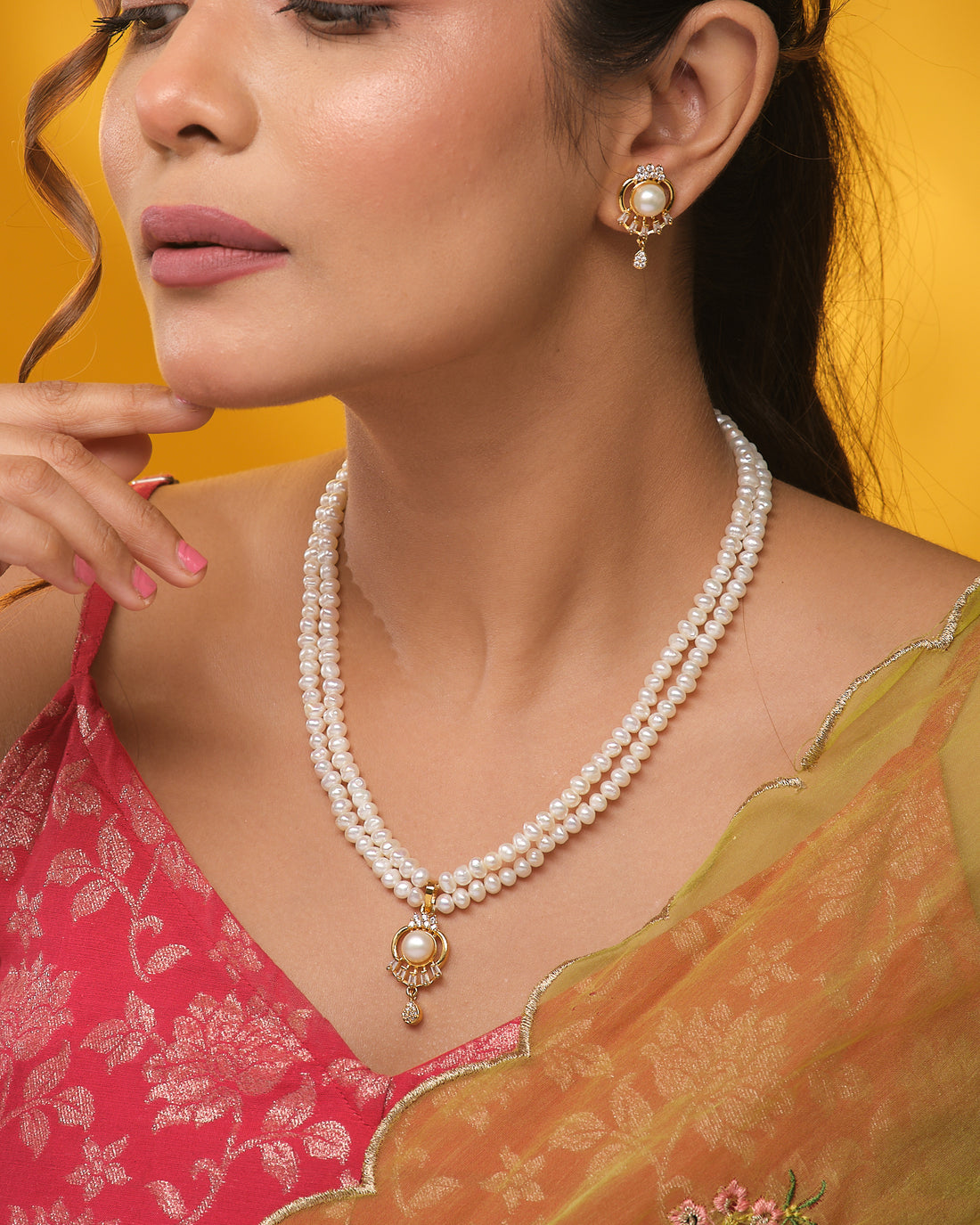The Chandrani Pearls Sparkling Halo CZ necklace is displayed on a navy blue stand, paired with matching stud earrings on either side, all radiating a luxurious shine.