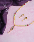 Add a pop of color with Chandrani Pearls’ Colorful One-Line Pearl Set with Earrings, featuring vibrant pearls and matching earrings, beautifully displayed on a pink surface beside elegant purple fabric.