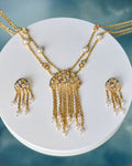 The Trendy Handcrafted Chain & CZ Necklace Set by Chandrani Pearls features colorful gemstones, CZ stones, and pearls in a multi-chain design with matching earrings, elegantly displayed on a white circular stand.