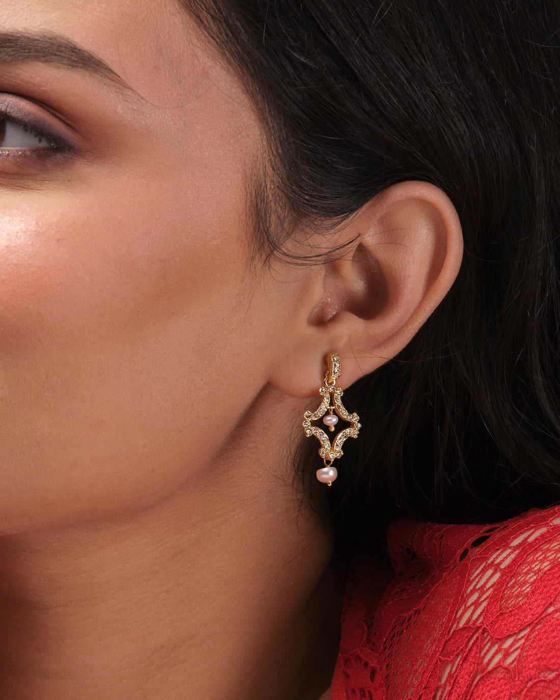 Delicate Pretty CZ Earrings by Chandrani Pearls India, featuring a classic design with rhinestones and pearl drops, are displayed on a white cube against a blurred floral background.