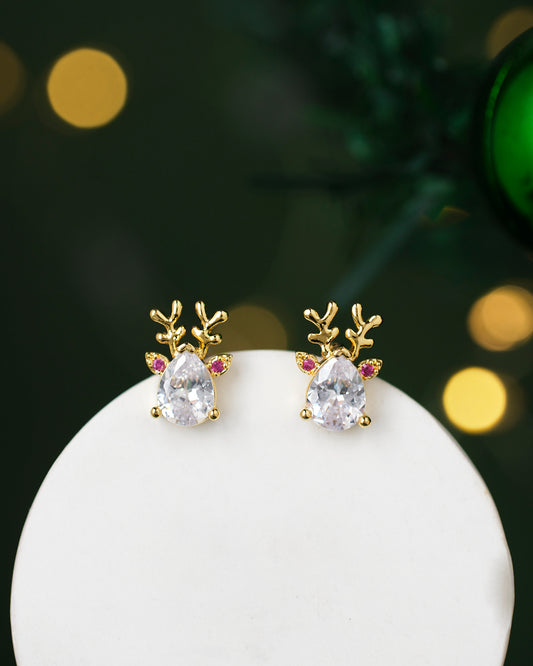 Chandrani Pearls' Sparkling Drip Earrings feature reindeer design with clear teardrop gems and pink accents, set against a white surface.