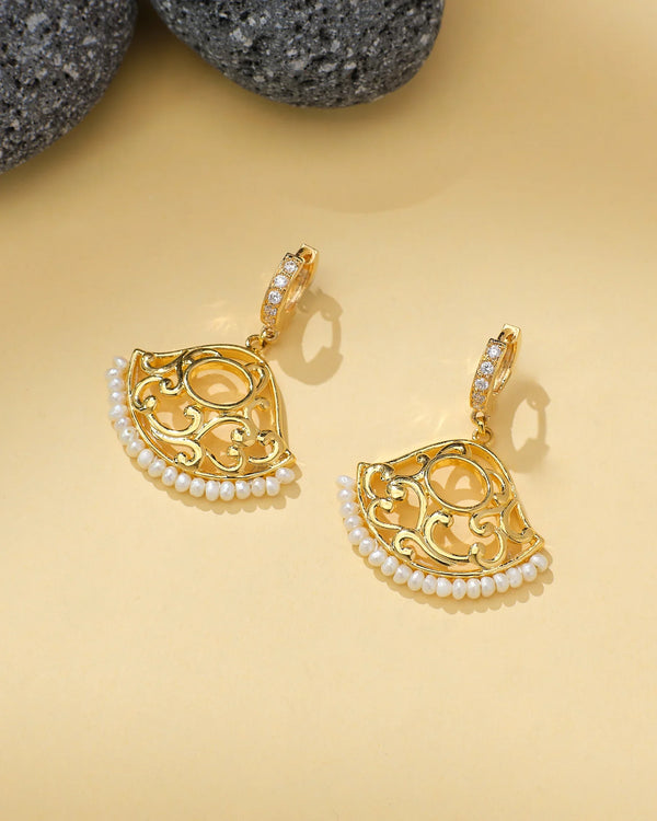 Chandrani Pearls' Floral CZ & Pearl Chandelier Earrings feature gold-toned filigree, pearl drops, and CZ-studded hoops—a chic festive statement perfect for weddings. Displayed on beige with stones nearby.